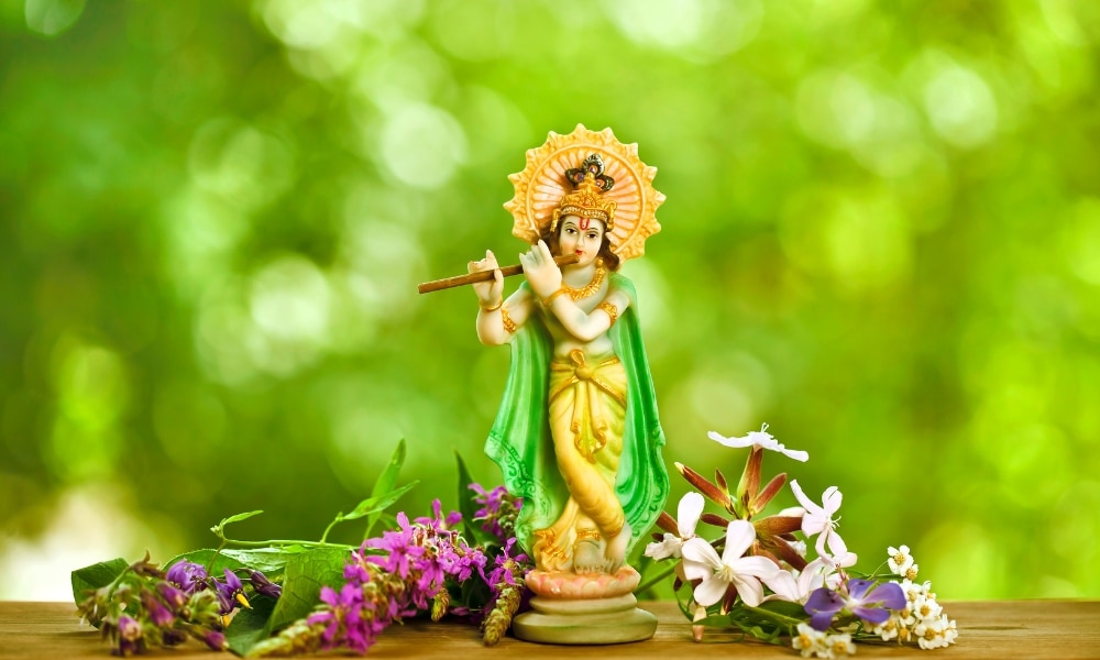 รูปปั้นเทพฮินดูเป่าขลุ่ยและดอกไม้