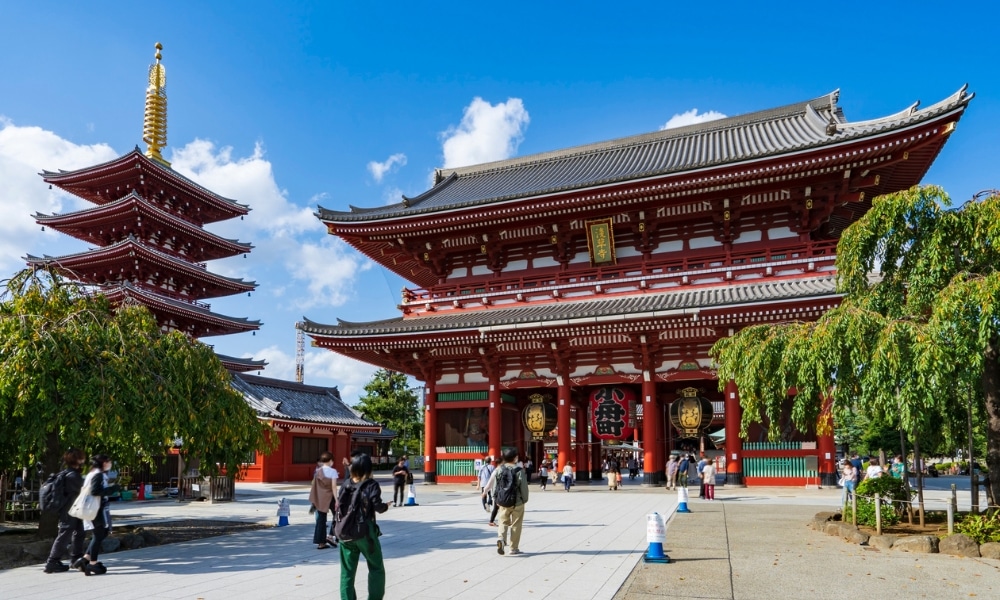 ผู้คนเดินอยู่ใกล้กับวัดเซ็นโซจิสีแดง ซึ่งเป็นสถานที่สักการะเทพเจ้าต่างประเทศที่มีชื่อเสียง และเจดีย์ห้าชั้นภายใต้ท้องฟ้าสีครามในกรุงโตเกียว ประเทศญี่ปุ่น.